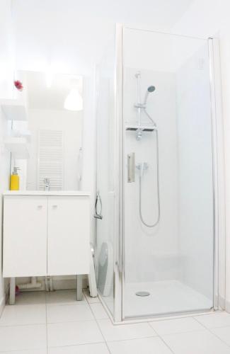 Baño blanco con ducha con puerta de cristal en Charming f2- private residence, en LʼÎle-Saint-Denis