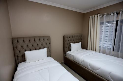 Cloud One Apartments في Kitwe: سريرين في غرفة صغيرة مع نافذة