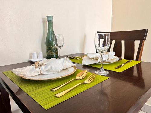 a dining table with a green bottle and glasses at Neema Executive Suites Near Junction Mall With Balcony in Nairobi