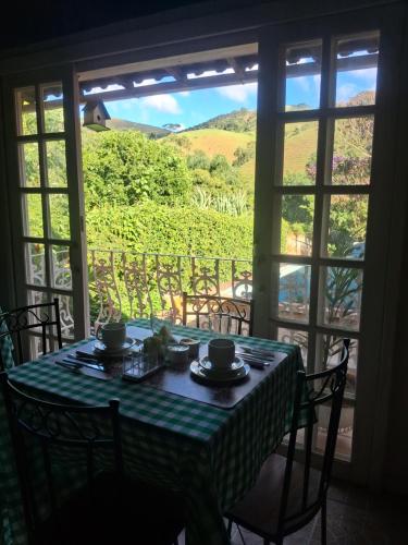 a table with a view of a vineyard through a window at Pousada Talho da Serra in Conservatória
