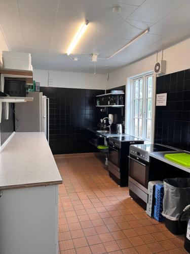 eine große Küche mit schwarz gefliesten Wänden und Arbeitsflächen in der Unterkunft Rønne Vandrerhjem in Rønne