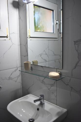 a bathroom with a sink and a mirror and a window at Venice Apartments in Limenaria
