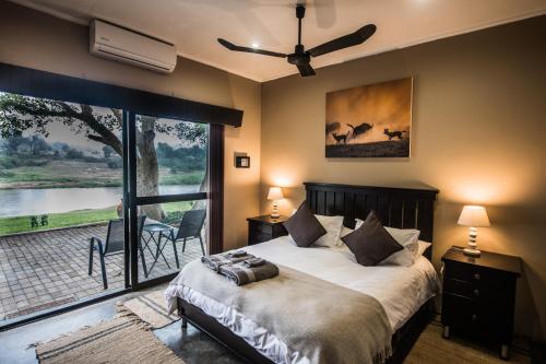 a bedroom with a bed and a large window at Maninghi Lodge in Balule Game Reserve