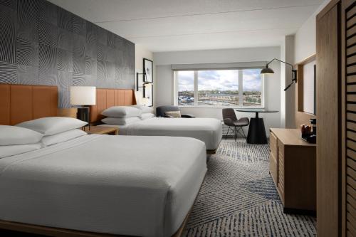 a hotel room with two beds and a desk at Sheraton Erie Bayfront Hotel in Erie
