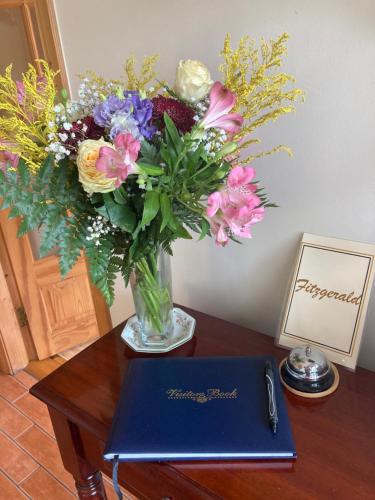 a vase of flowers on a table with a book at Inny River Lodge in Rathowen
