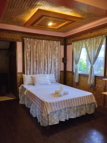 a bedroom with a large bed with white sheets and windows at Greenviews Resort & Restaurant Port Barton in San Vicente