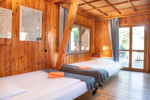 two beds in a room with wooden walls at Klimatyczna Chatka u Podnóża Góry in Porąbka