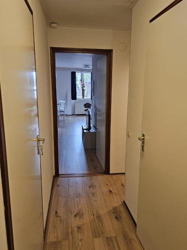 um corredor com duas portas e um quarto com piso de madeira em City Centre Suite em Hoorn