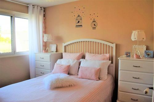 a bedroom with a bed with pink and white pillows at Appartement entièrement rénové avec SUPERBE VUE sur la Baie Sainte-Anne à TREGASTEL - Ref 96 in Trégastel
