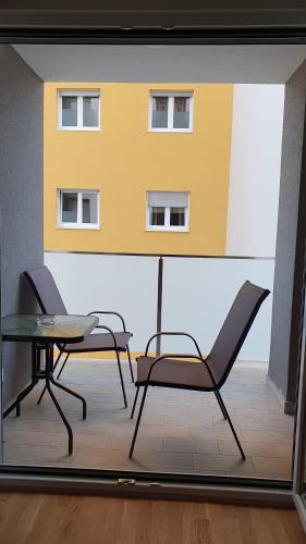 une fenêtre avec deux chaises et une table ainsi qu'un bâtiment dans l'établissement Odmor u Podgorici., à Podgorica