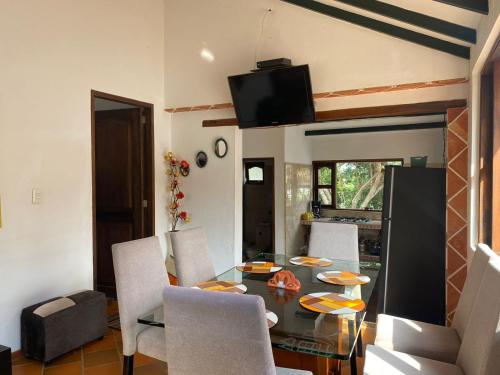Un comedor con una mesa de cristal y sillas. en CABAÑA VILLA SOFÍA RITOQUE, en Villa de Leyva