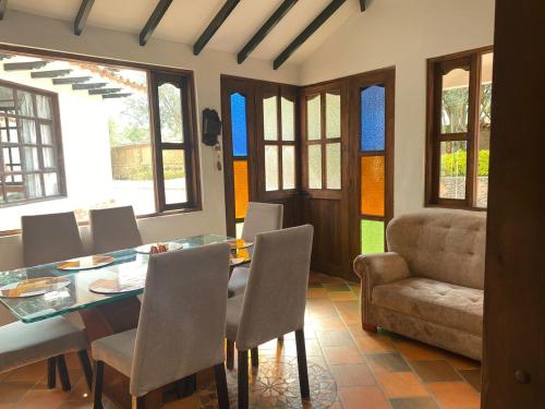 Un comedor con una mesa y sillas y un sofá. en CABAÑA VILLA SOFÍA RITOQUE, en Villa de Leyva