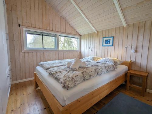ein Schlafzimmer mit einem Bett in einem Zimmer mit Holzwänden in der Unterkunft Op Lundingland in Ockholm