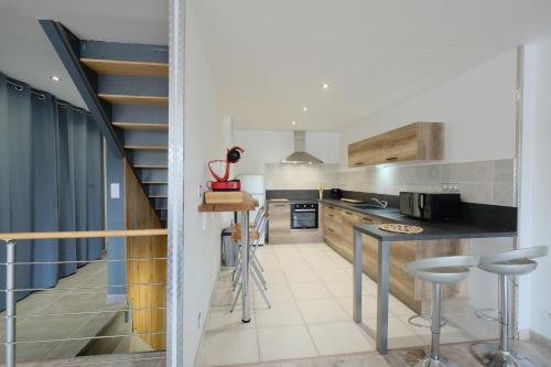 une cuisine avec un escalier menant à un loft dans l'établissement Aux portes du marché, à Bar-le-Duc