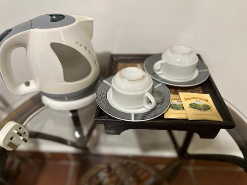 two cups and plates on a table with a tea kettle at Armenian Suite in George Town