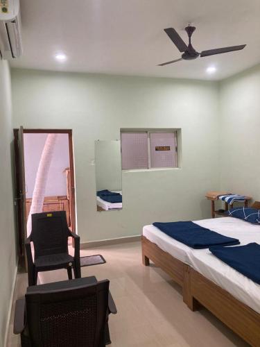 a bedroom with a bed and a chair and a ceiling fan at Oceanic Stay And Restaurant Gokarna in Gokarn