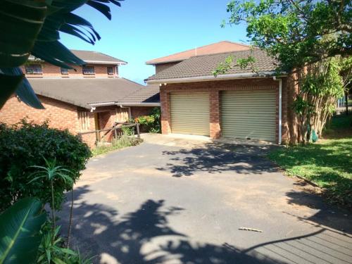 a driveway in front of a house with a garage at Mantis and Moon Surf Paradise & Adventure Lodge in Hibberdene