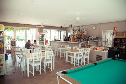 un restaurante con mesa de billar, mesas y sillas en Camping Sènia Riu, en Sant Pere Pescador