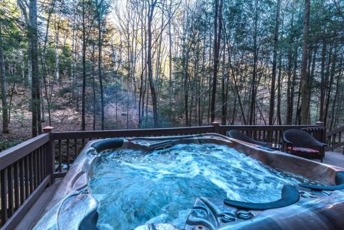 a hot tub on a deck with a view of the woods at Private Creekside Cabin+Hot Tub,Pool Table, & Pets in Ellijay