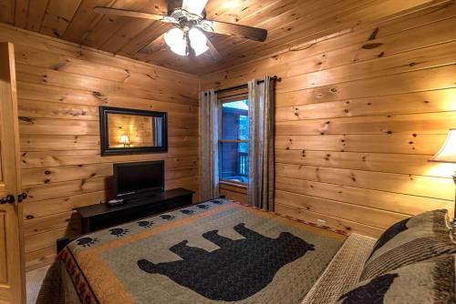 a log cabin bedroom with a bed and a television at Private Creekside Cabin+Hot Tub,Pool Table, & Pets in Ellijay