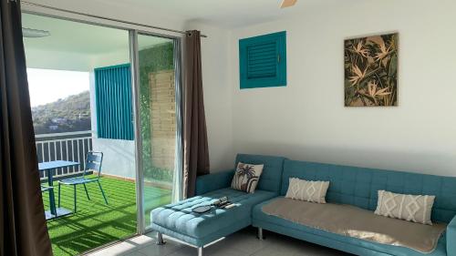 sala de estar con sofá azul y balcón en Appartement Ciel et Mer, en Schœlcher