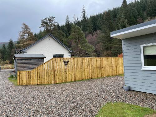 a wooden fence in front of a house at Rowan Bank Retreat in Fort Augustus