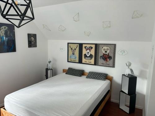 a bedroom with a white bed and pictures on the wall at Belle villa 150 m Carnac plage in Carnac