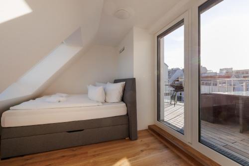 Bett in einem Zimmer mit einem großen Fenster in der Unterkunft SYMPHONY Apartments 40 - Modern Loft with Terrace and Grill in Central Location in Wien