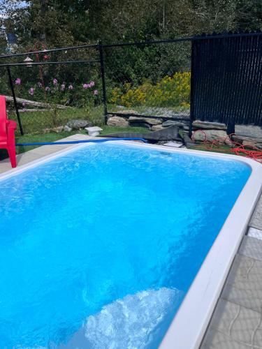 a blue swimming pool with a red chair next to it at Le Studio CITQ3O1849 in Saint Pierre de Broughton