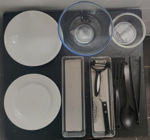 - une table avec des assiettes et des ustensiles blancs dans l'établissement Tiny house - Gare Paris Aeroport, à Drancy