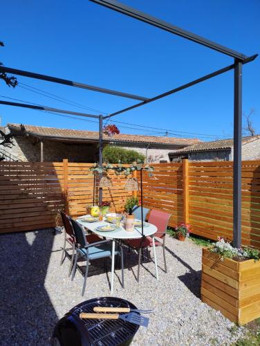 un patio con mesa, sillas y una valla en Gites l’Olivier avec piscine, en Vallon-Pont-dʼArc