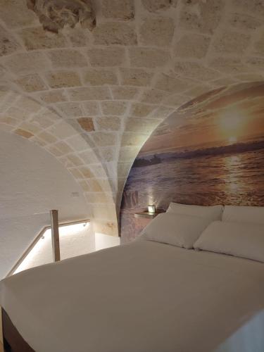 a white bed in a room with a stone wall at Dimora Fajano in Fasano