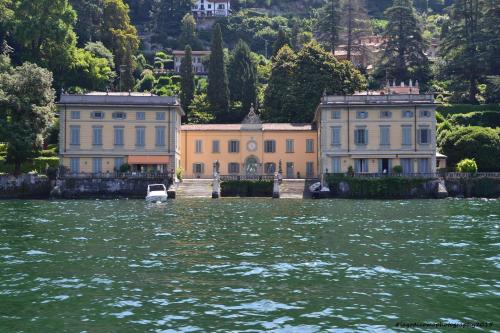 two buildings on the water in front of a mountain at Appartamento Country House Menaggio in Menaggio
