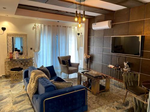 ein Wohnzimmer mit einem blauen Sofa und einem TV in der Unterkunft SAPHYR GROUP HOTELIER in Douala