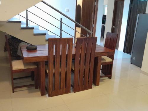 a wooden dining room table with chairs and stairs at Luxury 3BHK Villa With Swimming Pool in Candolim in Candolim