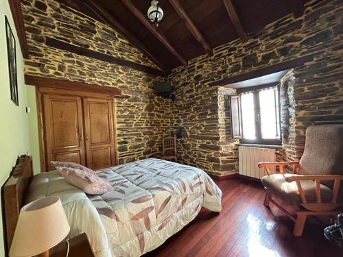 1 dormitorio con cama y pared de piedra en Casa Freixe Apartamentos Rurales, en Santa Eulalia de Oscos