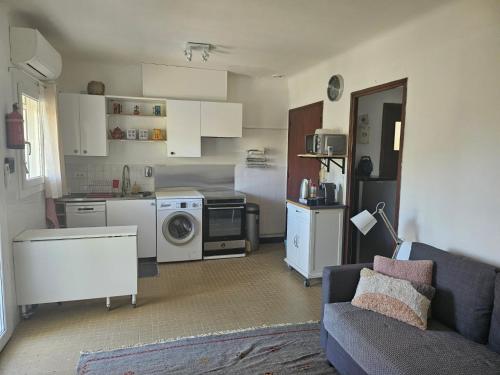 un salon avec un canapé et une cuisine dans l'établissement Les Lambrusques T2 avec jardin à 300 m de la plage, à Cavalaire-sur-Mer