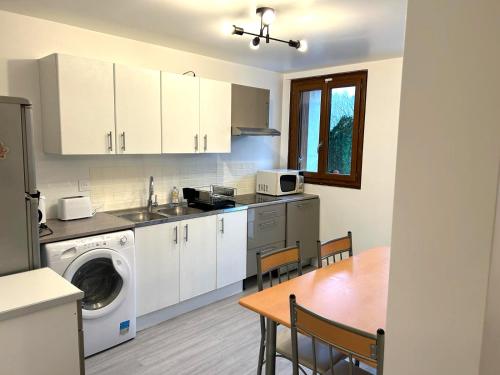 a kitchen with a washing machine and a table with chairs at Appartement calme Antony, terrasse, vue jardin, proche Paris et Orly in Antony
