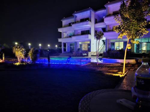 a white building with purple lights at night at ڤيلا السرايا in El-Qaṭṭa