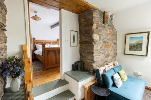 un soggiorno con camino in pietra e divano blu di HIGH TREES BYRE - Two bed Cottage with Log Burner & Incredible Views a Workington