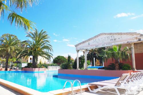 a swimming pool with white chairs and palm trees at Malibu Village in Canet-en-Roussillon