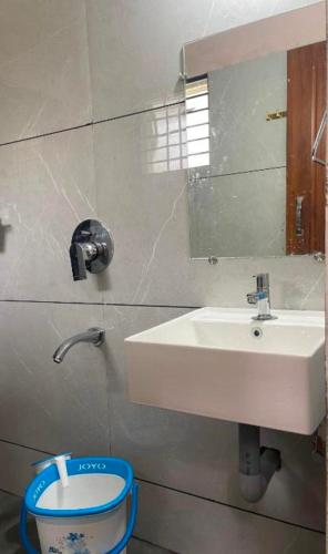 een badkamer met een witte wastafel en een spiegel bij The room for two in Madikeri