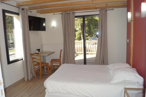 a bedroom with a bed and a table and a balcony at Auberge des Myrtilles in Saint-Bonnet-le-Froid