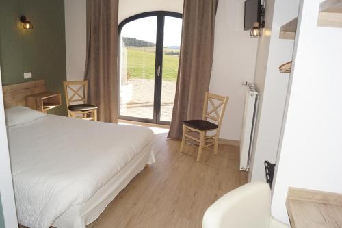 a bedroom with a bed and a large window at Auberge des Myrtilles in Saint-Bonnet-le-Froid
