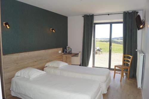 a hotel room with two beds and a sliding glass door at Auberge des Myrtilles in Saint-Bonnet-le-Froid