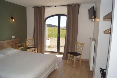 a bedroom with a bed and a sliding glass door at Auberge des Myrtilles in Saint-Bonnet-le-Froid