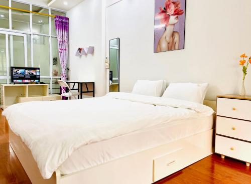 a bedroom with a large white bed and a desk at Liu homestay in Nà Phia