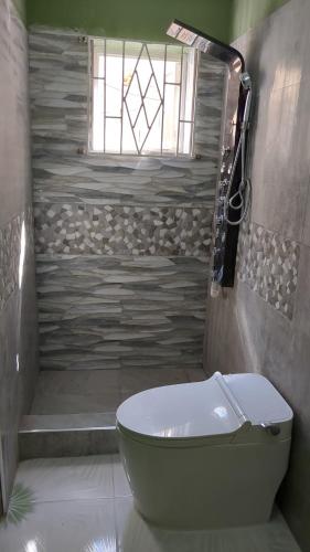 een badkamer met een toilet en een douche met een raam bij BridgeView Arcadia in Portmore