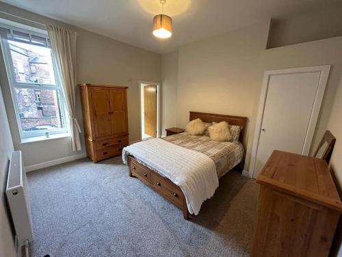 a bedroom with a bed and a dresser and a window at Apartment 381 in Jesmond