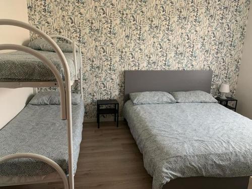 1 dormitorio con 2 literas y pared con papel pintado en Appartamento a Ravenna - 100 metri dalla spiaggia en Lido Adriano